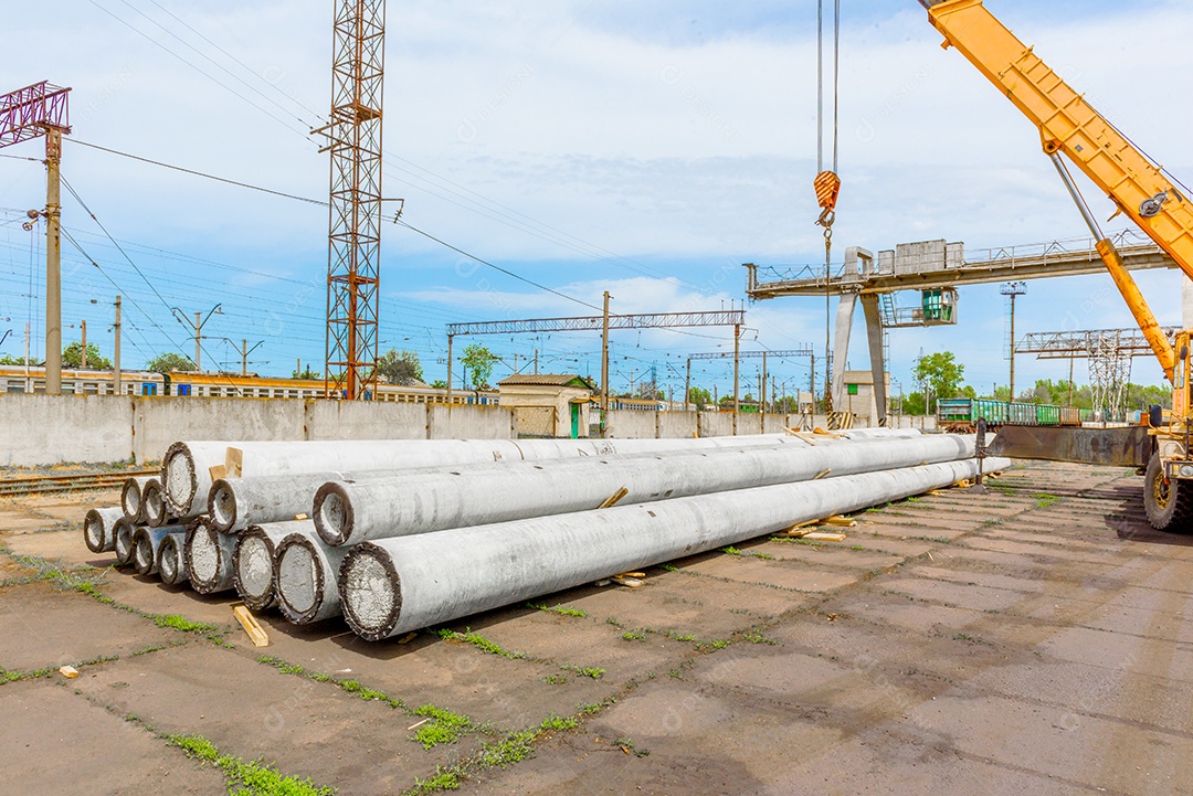 Descarga de postes de concreto de alta tensão no canteiro de obras por meio de guindaste. Preparação para instalação de linha de alta tensão