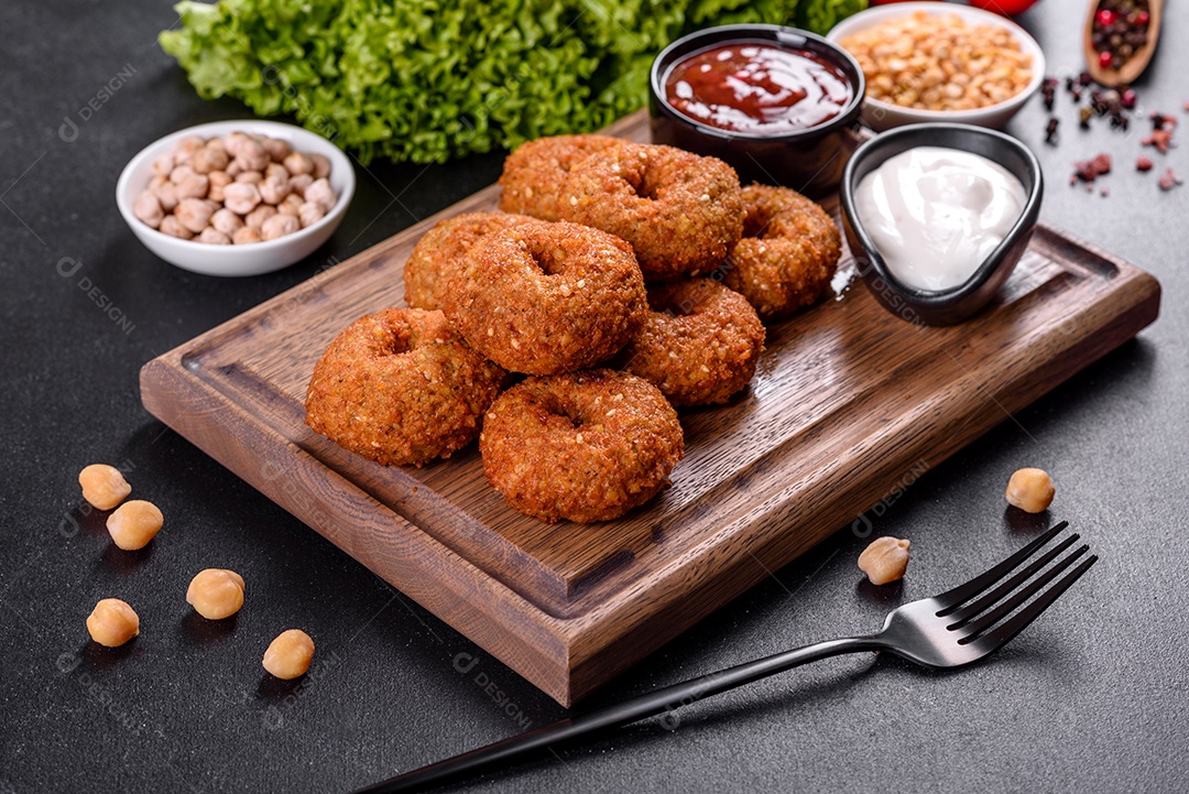 Lindo delicioso falafel de grão de bico fresco com molhos em um fundo de concreto. Elementos da culinária vegetariana