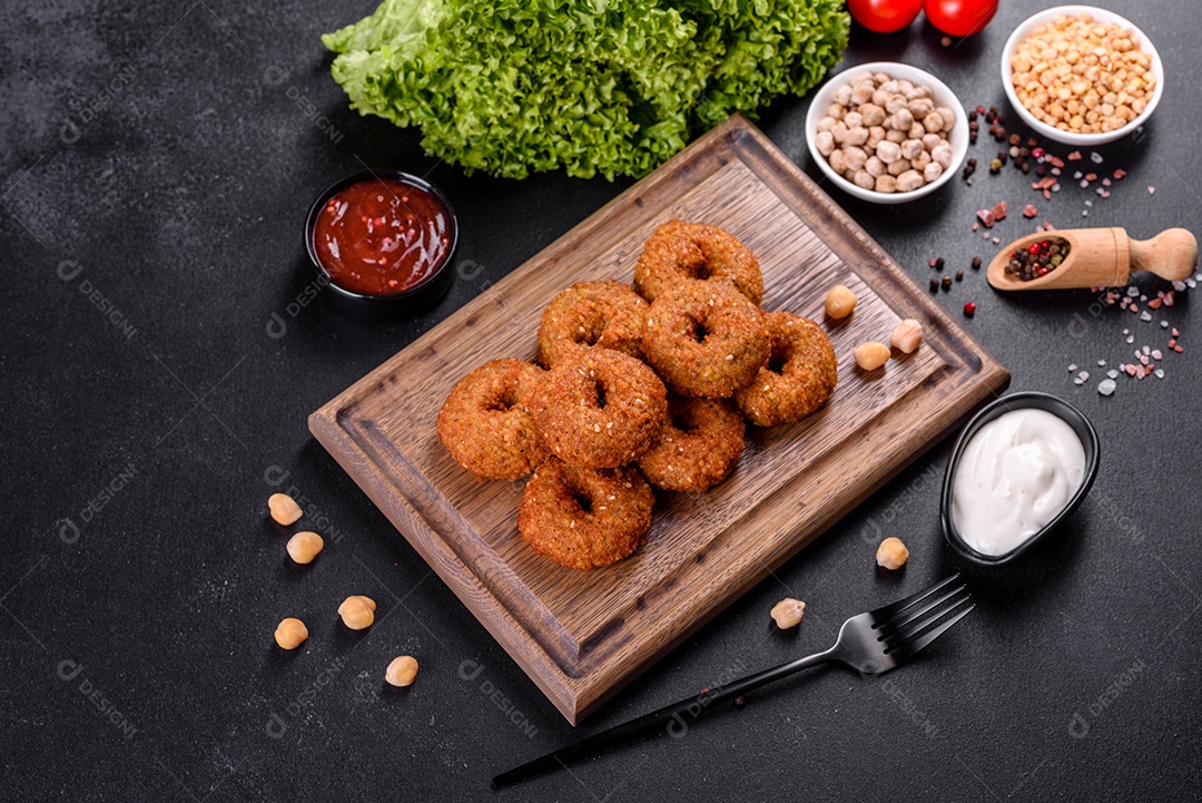 Lindo delicioso falafel de grão de bico fresco com molhos em um fundo de concreto. Elementos da culinária vegetariana