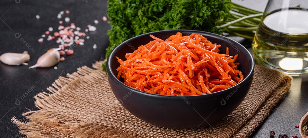 Deliciosas cenouras coreanas suculentas e picantes em pratos cerâmicos sobre um fundo escuro de concreto. Cozinha asiática