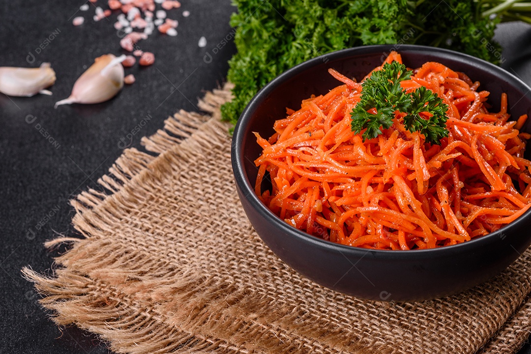 Deliciosas cenouras coreanas suculentas e picantes em pratos cerâmicos sobre um fundo escuro de concreto. Cozinha asiática
