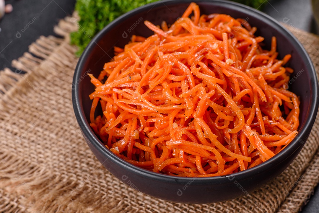 Deliciosas cenouras coreanas suculentas e picantes em pratos cerâmicos sobre um fundo escuro de concreto. Cozinha asiática