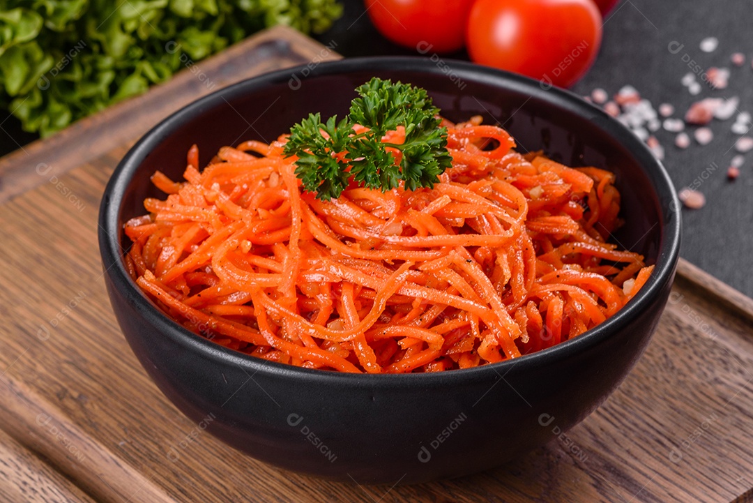 Deliciosas cenouras coreanas suculentas e picantes em pratos cerâmicos sobre um fundo escuro de concreto. Cozinha asiática