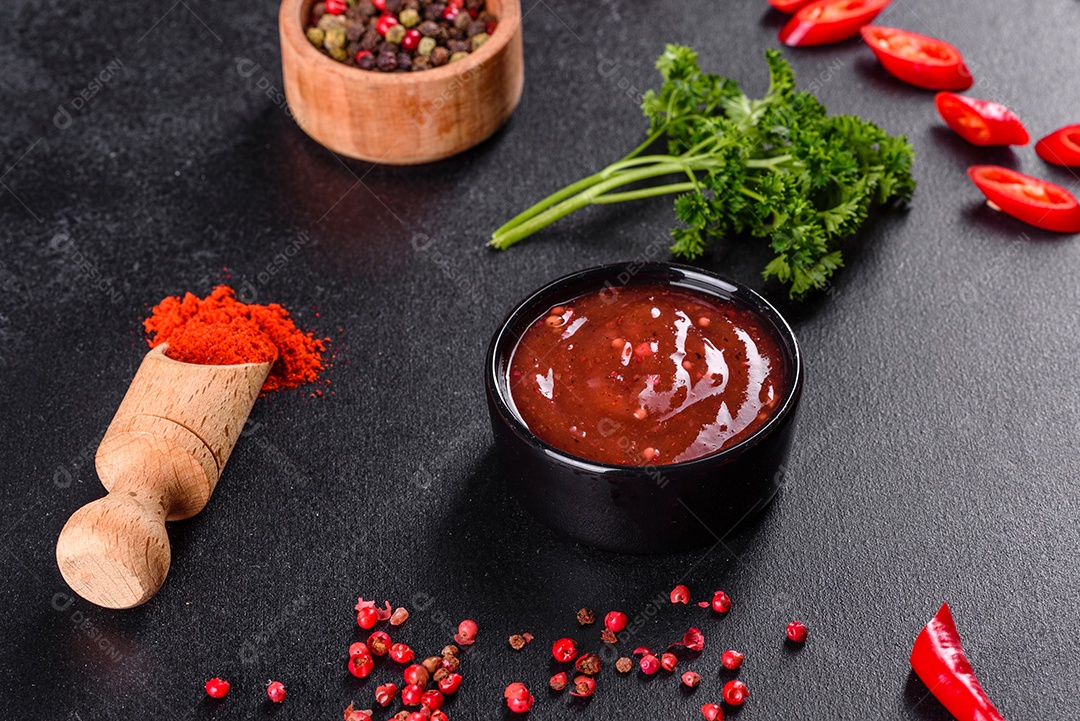 Tempero picante da culinária georgiana adjika em uma tigela com pimenta vermelha e alho em uma mesa de concreto fechada