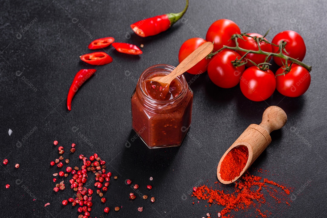 Tempero picante da culinária georgiana adjika em uma tigela com pimenta vermelha e alho em uma mesa de concreto fechada