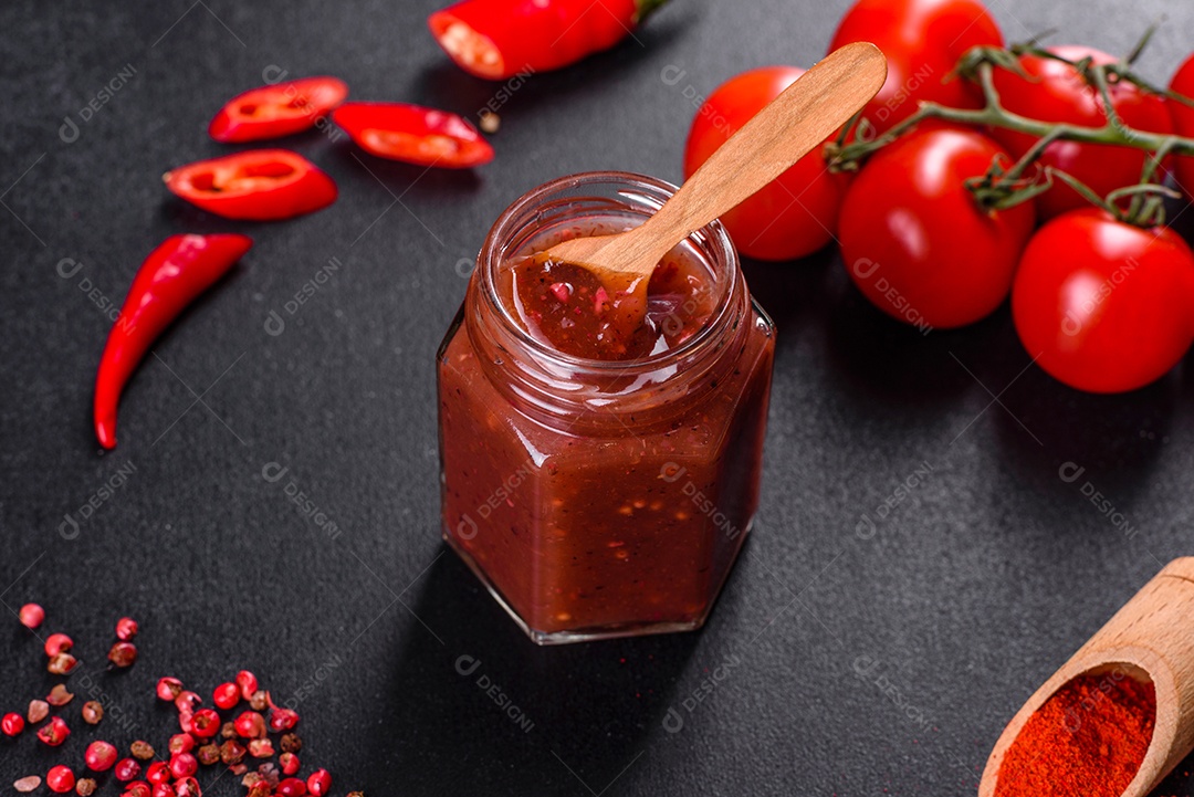 Tempero picante da culinária georgiana adjika em uma tigela com pimenta vermelha e alho em uma mesa de concreto fechada