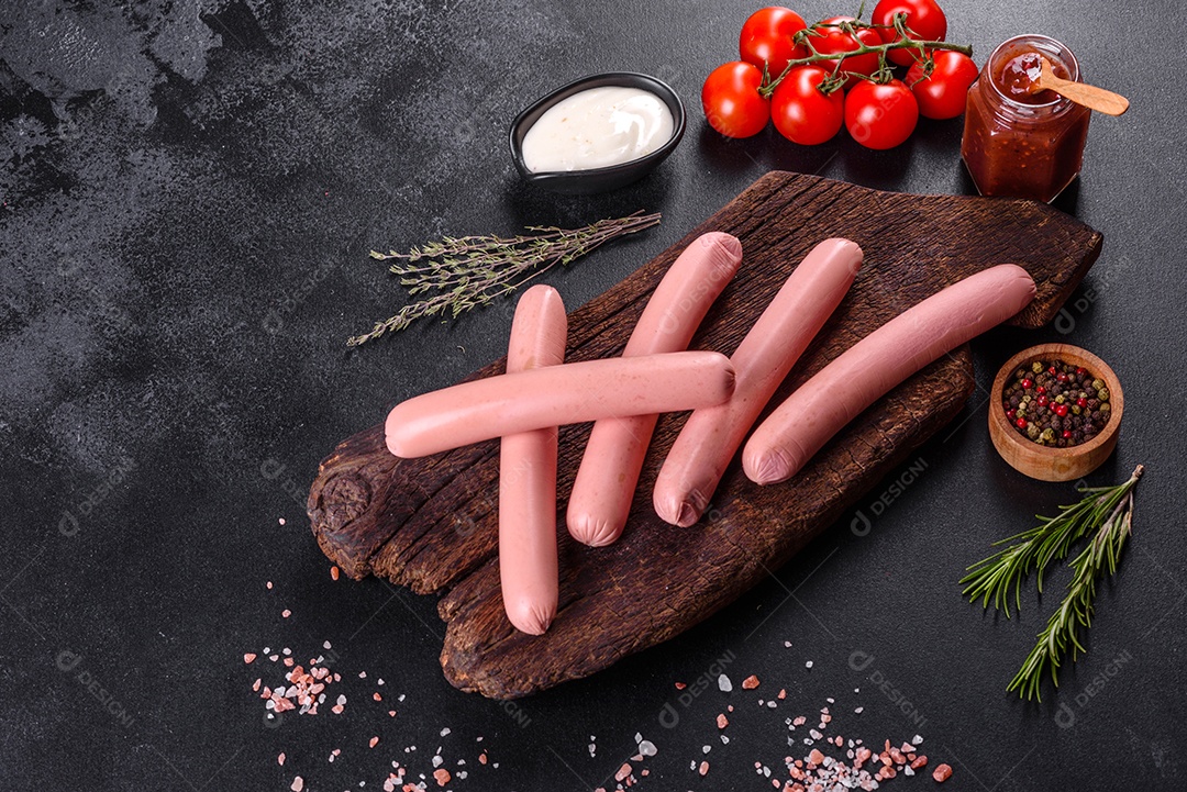 Deliciosas salsichas frescas cozidas com legumes e especiarias sobre um fundo escuro de concreto