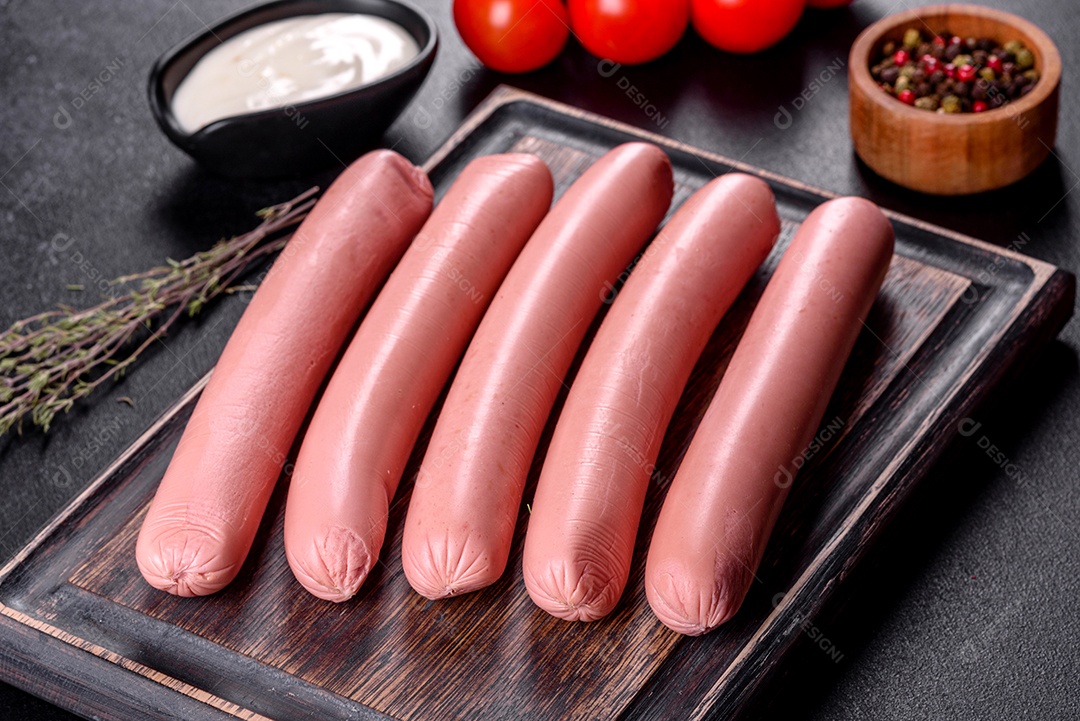 Deliciosas salsichas frescas cozidas com legumes e especiarias sobre um fundo escuro de concreto