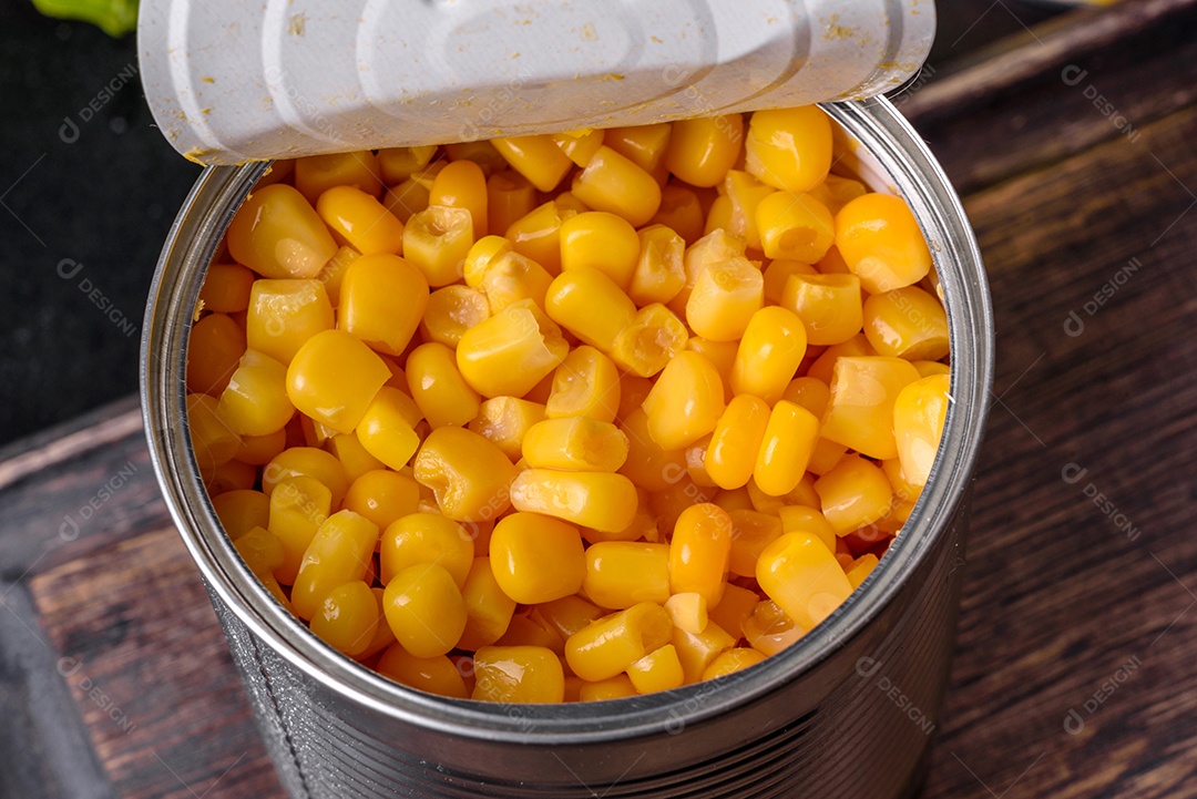 Milho enlatado fresco e delicioso em uma tábua de madeira sobre um fundo escuro de concreto