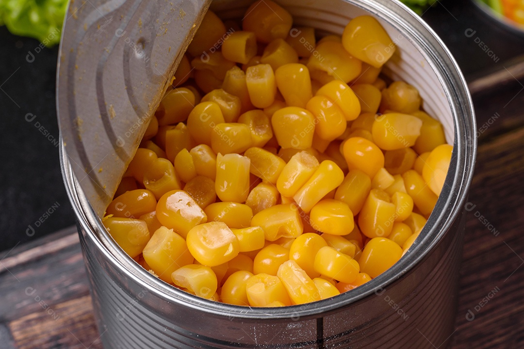 Milho enlatado fresco e delicioso em uma tábua de madeira sobre um fundo escuro de concreto