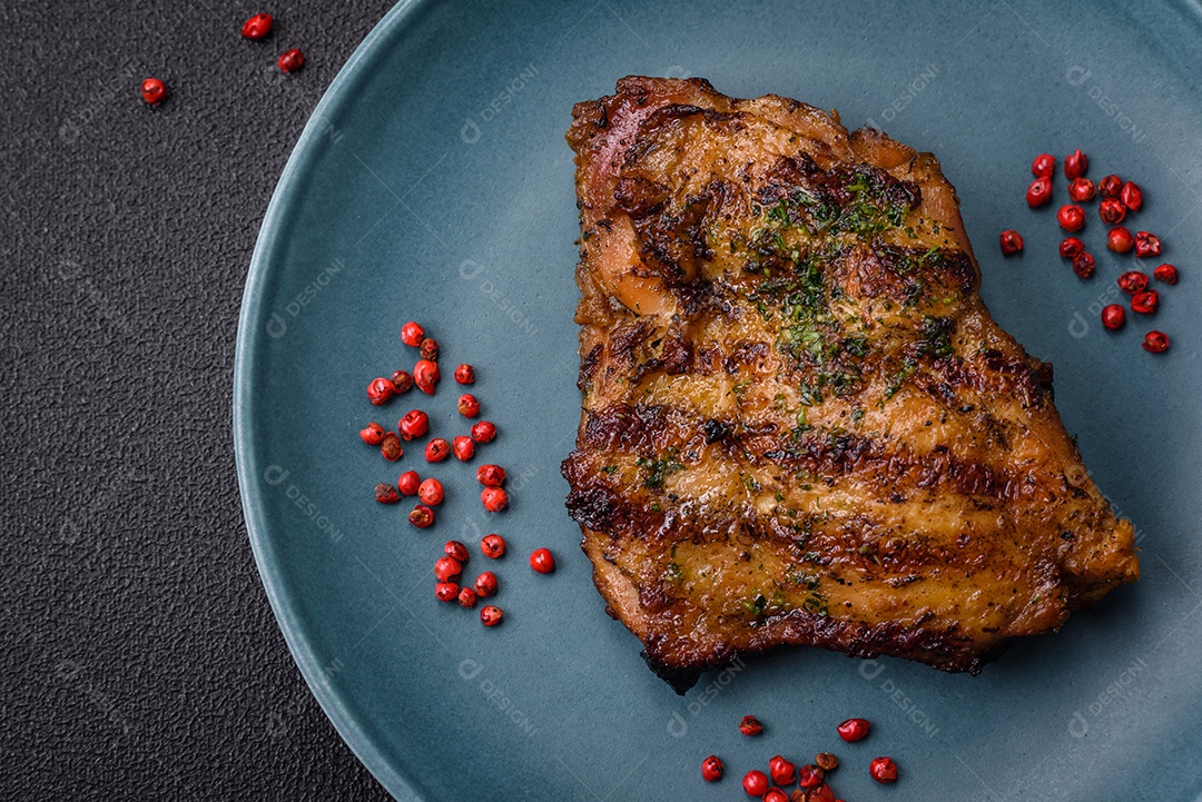 Delicioso bife suculento ou bife de frango com sal, especiarias e ervas sobre um fundo escuro de concreto