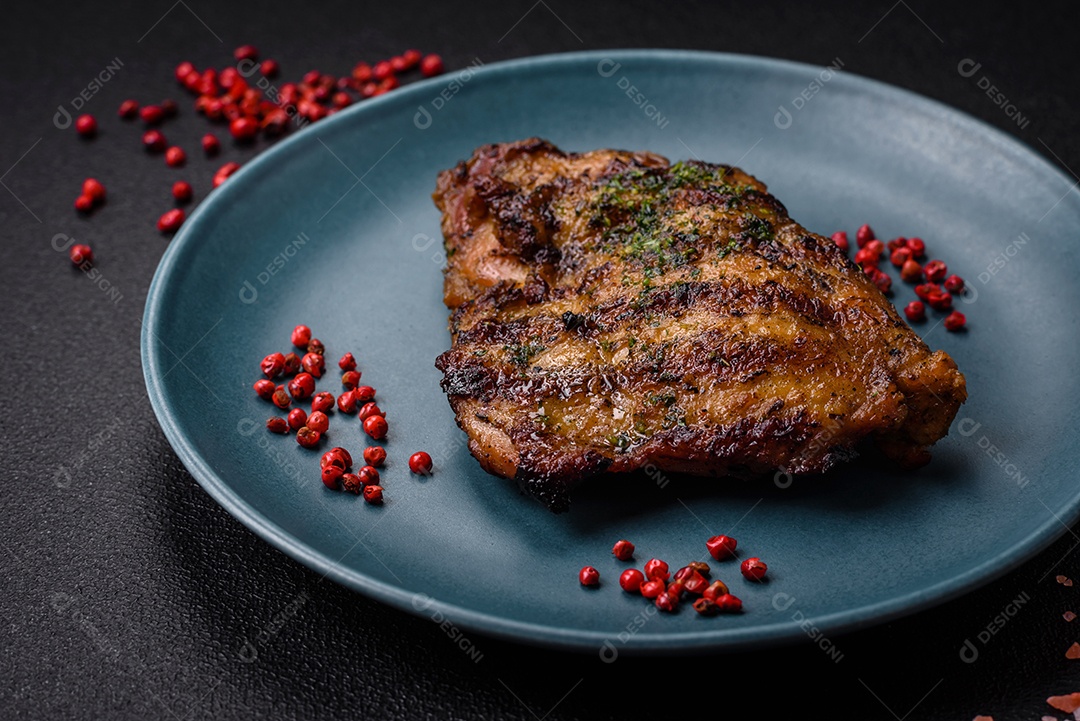 Delicioso bife suculento ou bife de frango com sal, especiarias e ervas sobre um fundo escuro de concreto