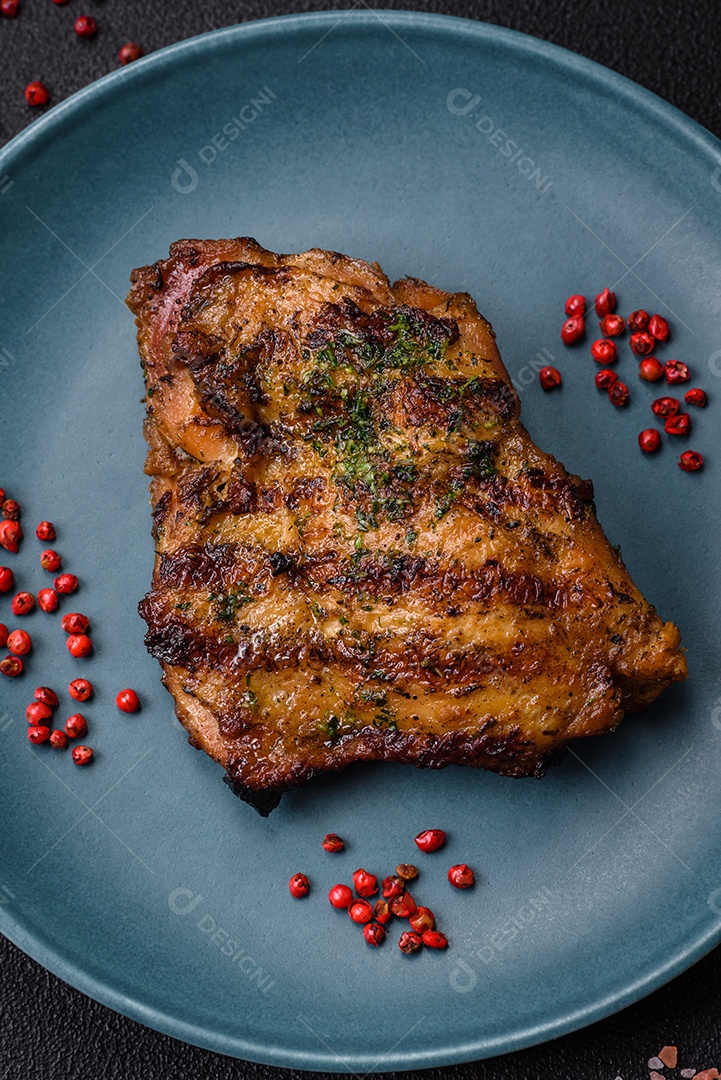 Delicioso bife suculento ou bife de frango com sal, especiarias e ervas sobre um fundo escuro de concreto