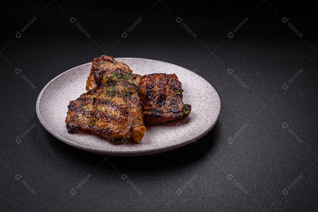 Delicioso bife suculento ou bife de frango com sal, especiarias e ervas sobre um fundo escuro de concreto