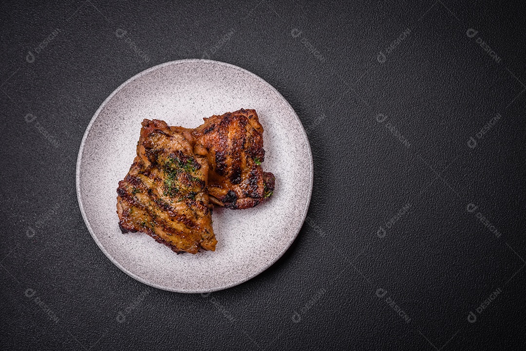 Delicioso bife suculento ou bife de frango com sal, especiarias e ervas sobre um fundo escuro de concreto