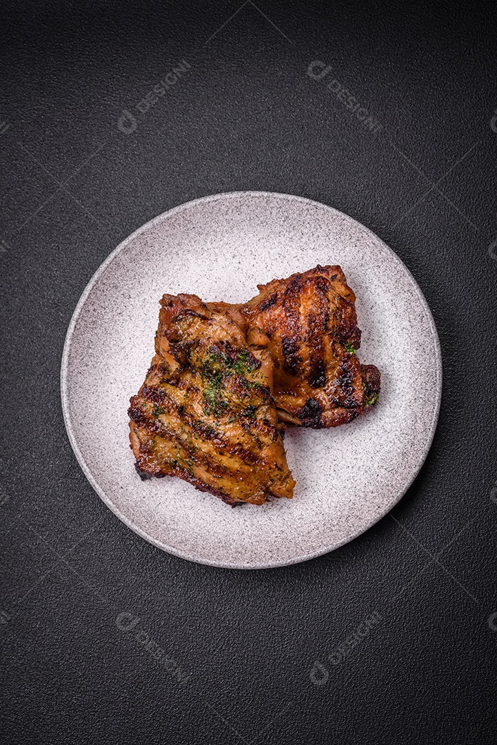 Delicioso bife suculento ou bife de frango com sal, especiarias e ervas sobre um fundo escuro de concreto