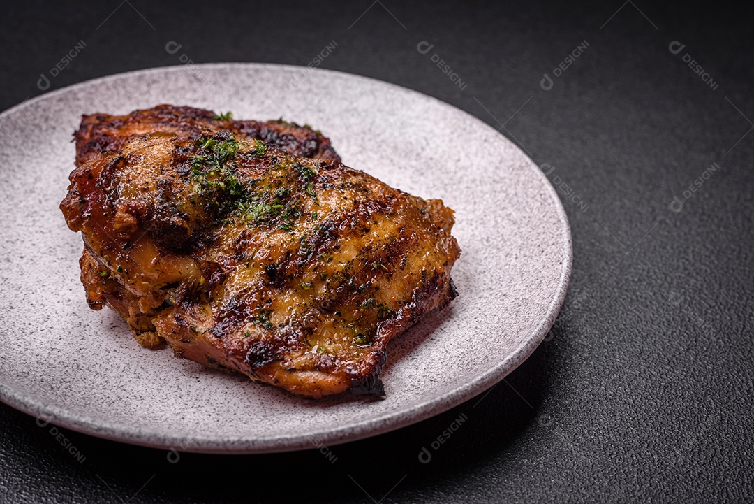 Delicioso bife suculento ou bife de frango com sal, especiarias e ervas sobre um fundo escuro de concreto