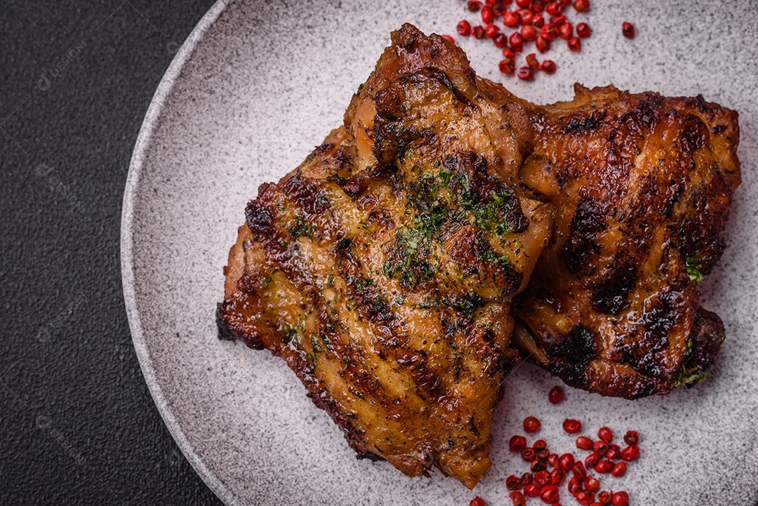 Delicioso bife suculento ou bife de frango com sal, especiarias e ervas sobre um fundo escuro de concreto