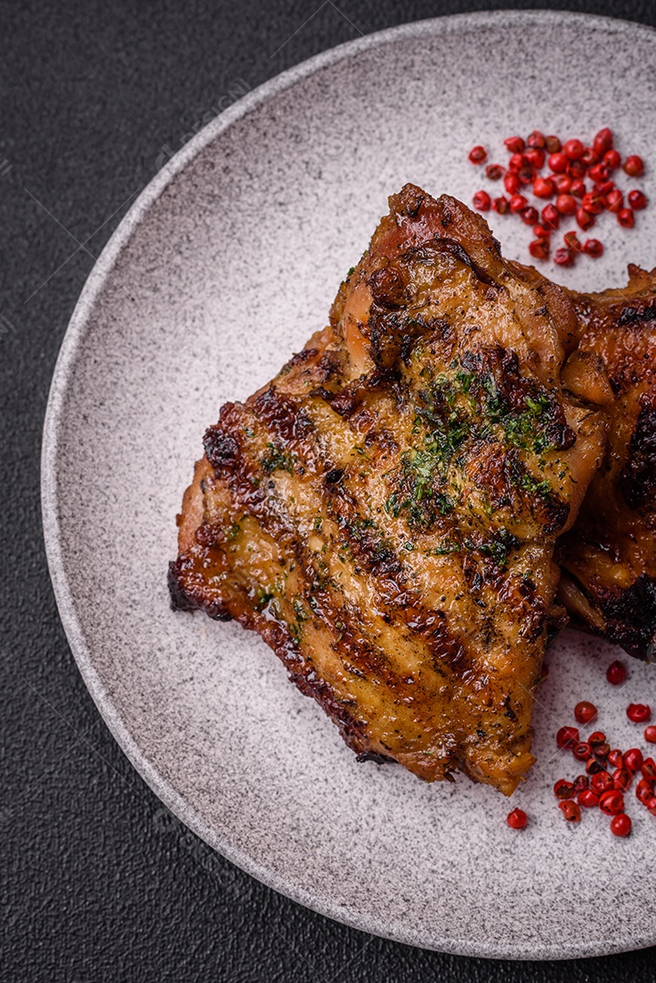 Delicioso bife suculento ou bife de frango com sal, especiarias e ervas sobre um fundo escuro de concreto