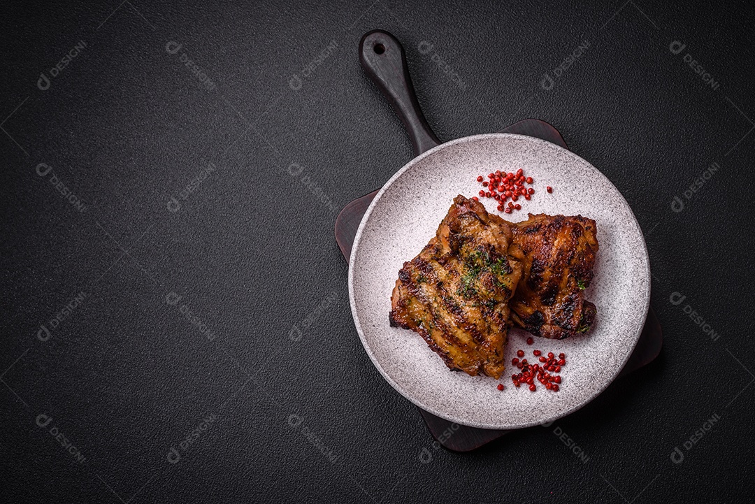 Delicioso bife suculento ou bife de frango com sal, especiarias e ervas sobre um fundo escuro de concreto