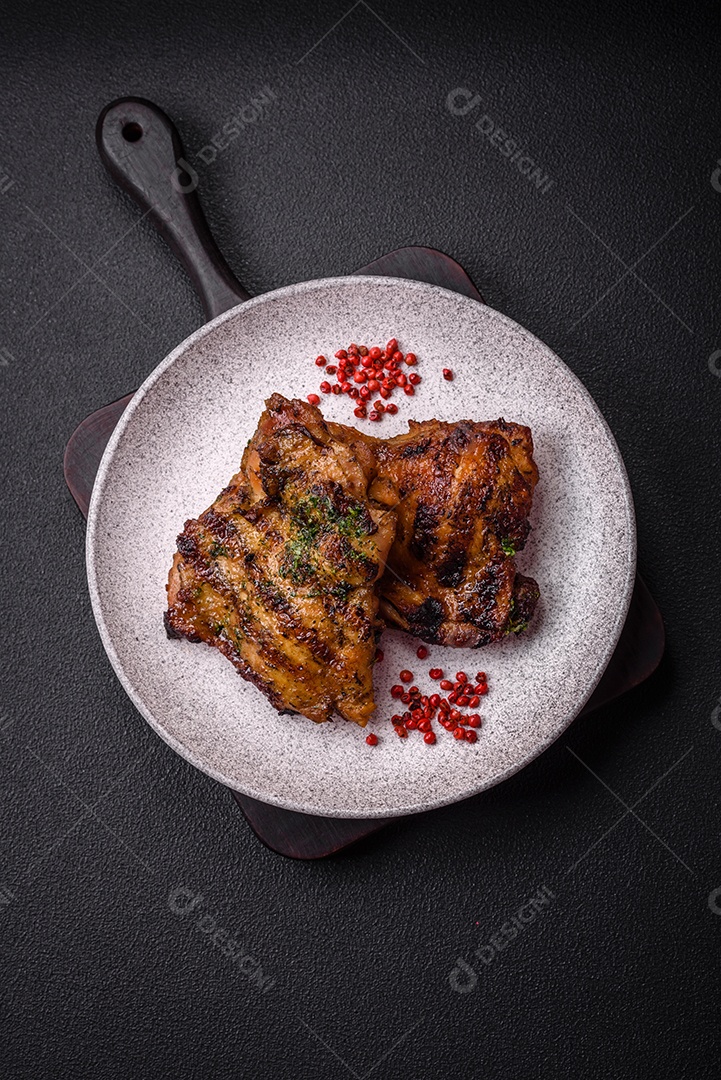 Delicioso bife suculento ou bife de frango com sal, especiarias e ervas sobre um fundo escuro de concreto