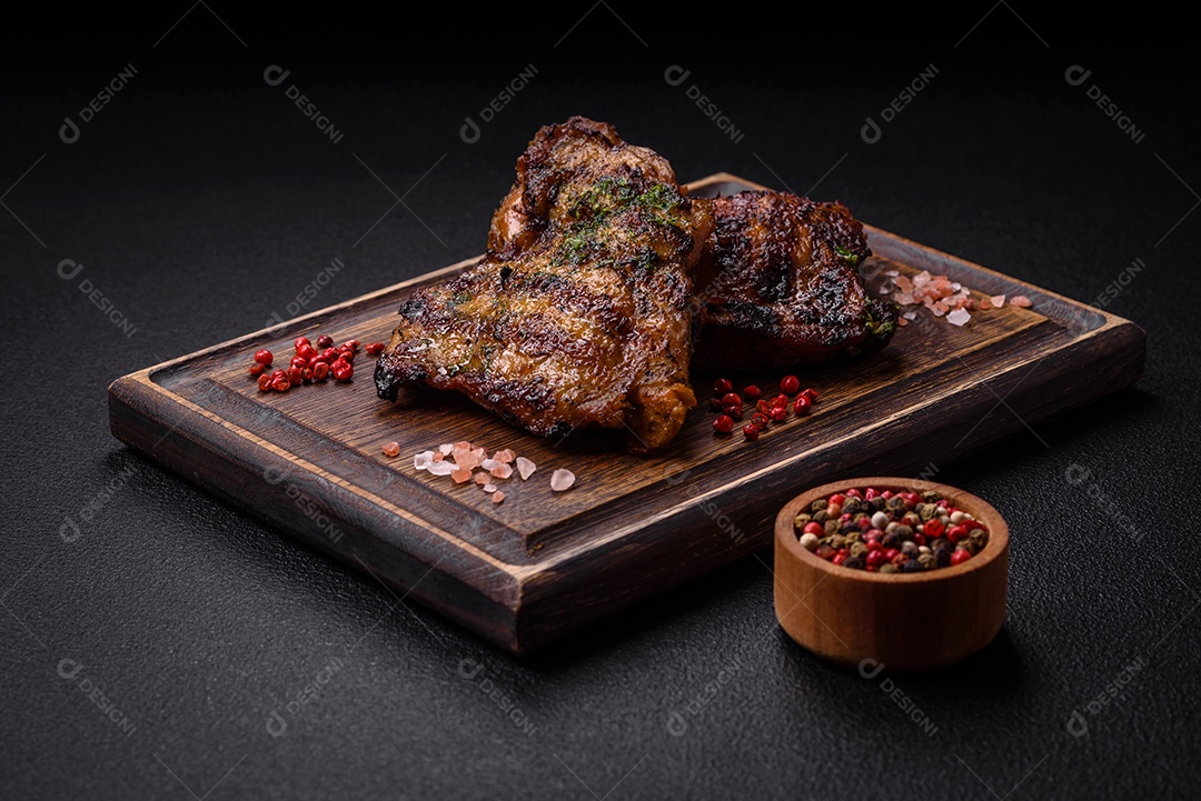 Delicioso bife suculento ou bife de frango com sal, especiarias e ervas sobre um fundo escuro de concreto