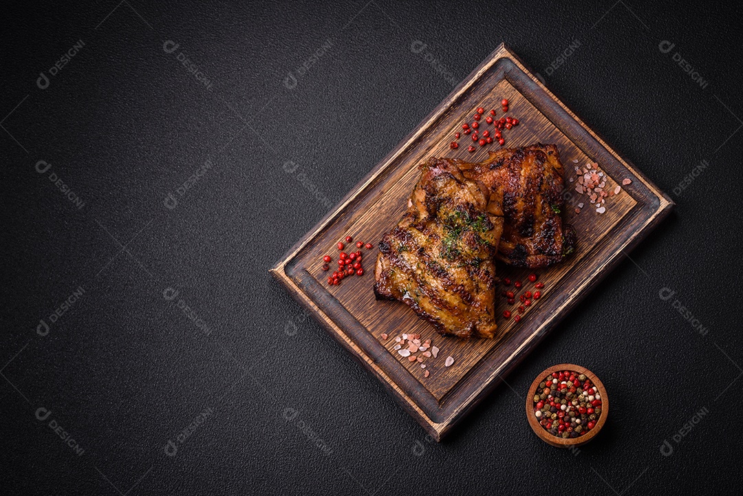 Delicioso bife suculento ou bife de frango com sal, especiarias e ervas sobre um fundo escuro de concreto