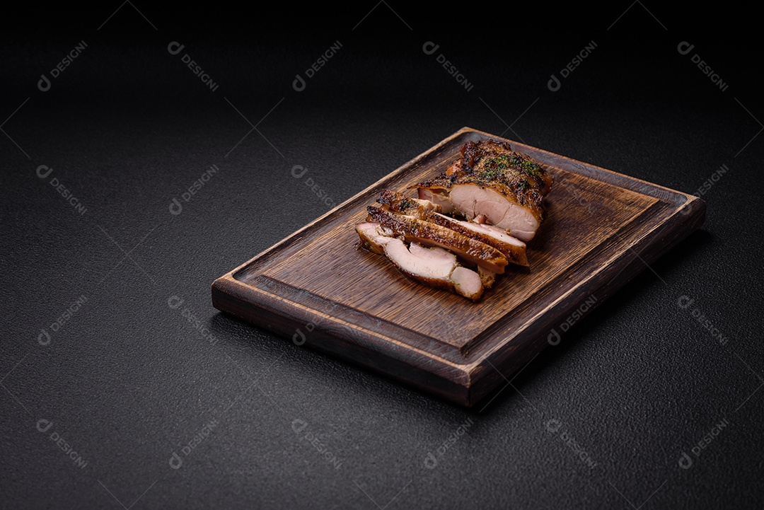 Delicioso bife suculento ou bife de frango com sal, especiarias e ervas sobre um fundo escuro de concreto