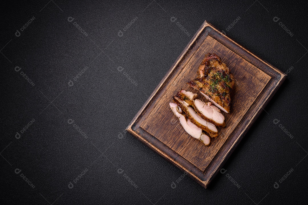 Delicioso bife suculento ou bife de frango com sal, especiarias e ervas sobre um fundo escuro de concreto