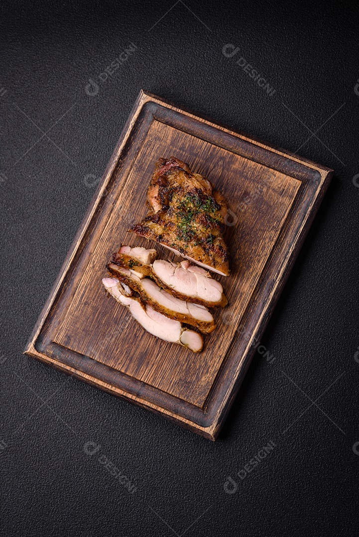 Delicioso bife suculento ou bife de frango com sal, especiarias e ervas sobre um fundo escuro de concreto