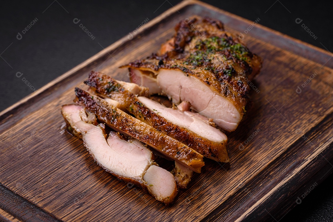 Delicioso bife suculento ou bife de frango com sal, especiarias e ervas sobre um fundo escuro de concreto