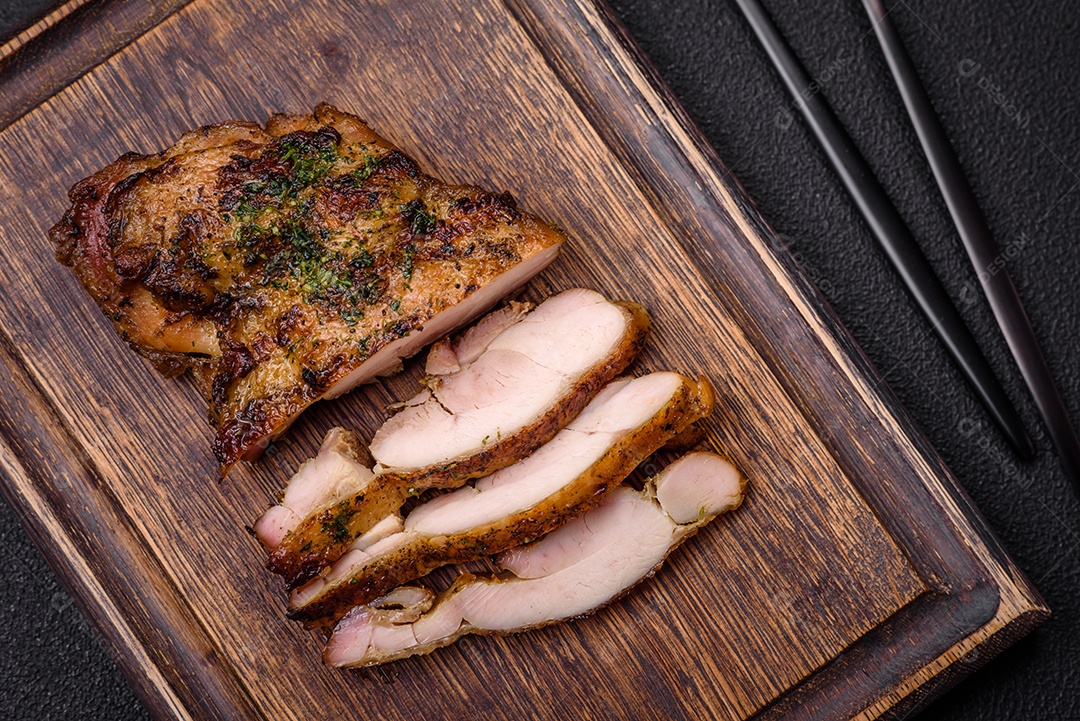 Delicioso bife suculento ou bife de frango com sal, especiarias e ervas sobre um fundo escuro de concreto