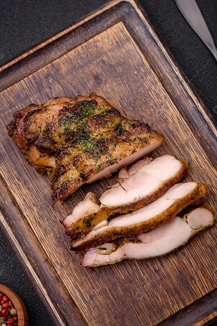 Delicioso bife suculento ou bife de frango com sal, especiarias e ervas sobre um fundo escuro de concreto