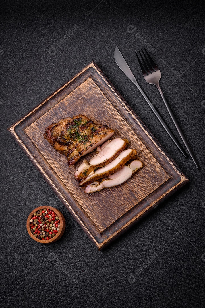 Delicioso bife suculento ou bife de frango com sal, especiarias e ervas sobre um fundo escuro de concreto