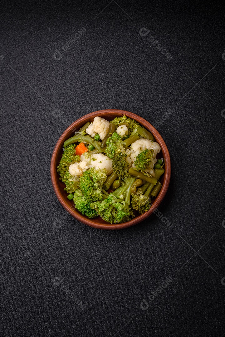 Deliciosos legumes frescos cozidos cenouras, brócolis, couve-flor em uma placa preta sobre um fundo escuro de concreto