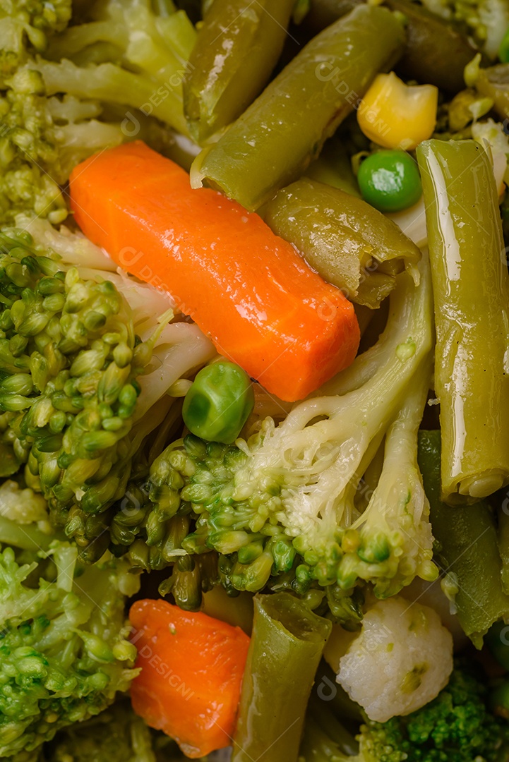 Deliciosos legumes frescos cozidos cenouras, brócolis, couve-flor em uma placa preta sobre um fundo escuro de concreto