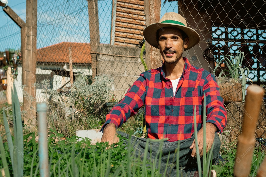 Agricultor de chapéu analisando a plantação ao pôr do sol