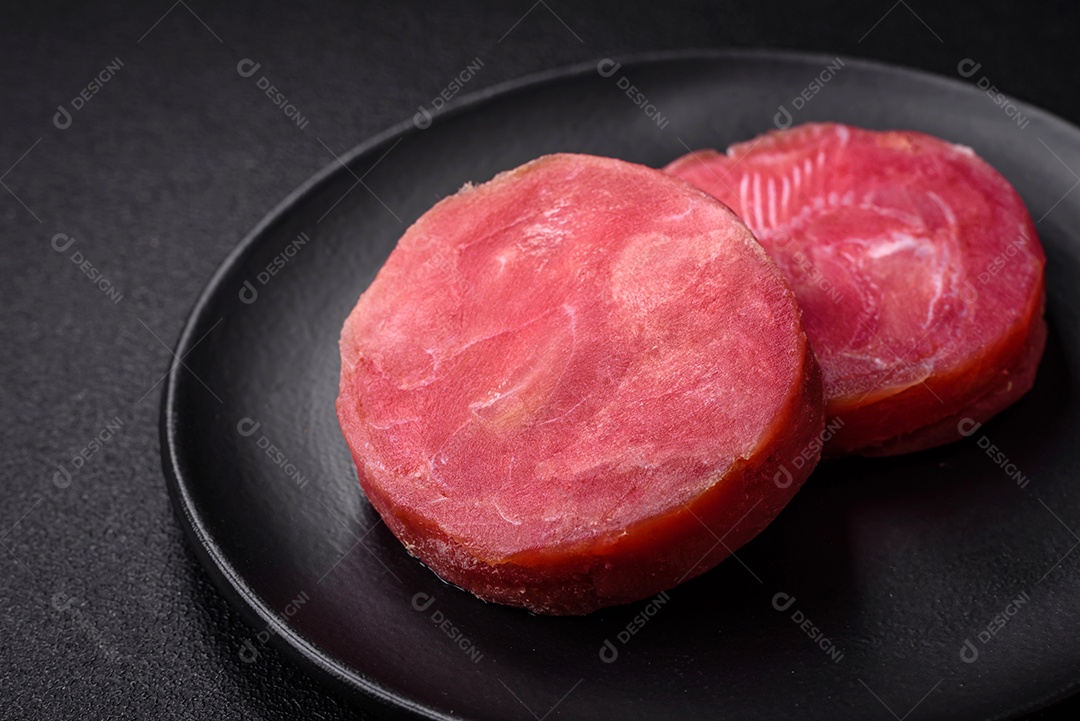 Bifes redondos de atum suculento cru com sal e especiarias sobre um fundo escuro de concreto