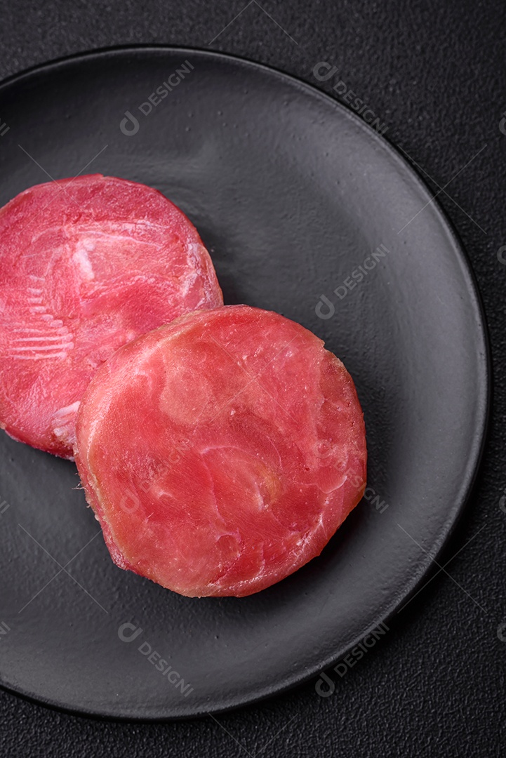 Bifes redondos de atum suculento cru com sal e especiarias sobre um fundo escuro de concreto