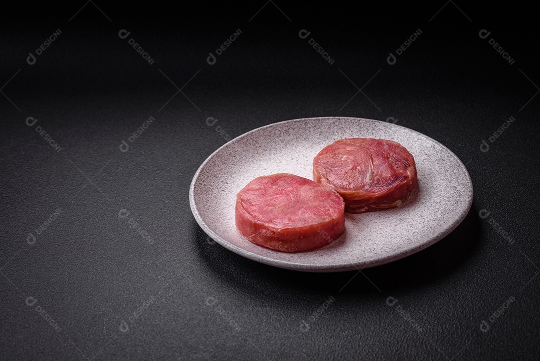 Bifes redondos de atum suculento cru com sal e especiarias sobre um fundo escuro de concreto