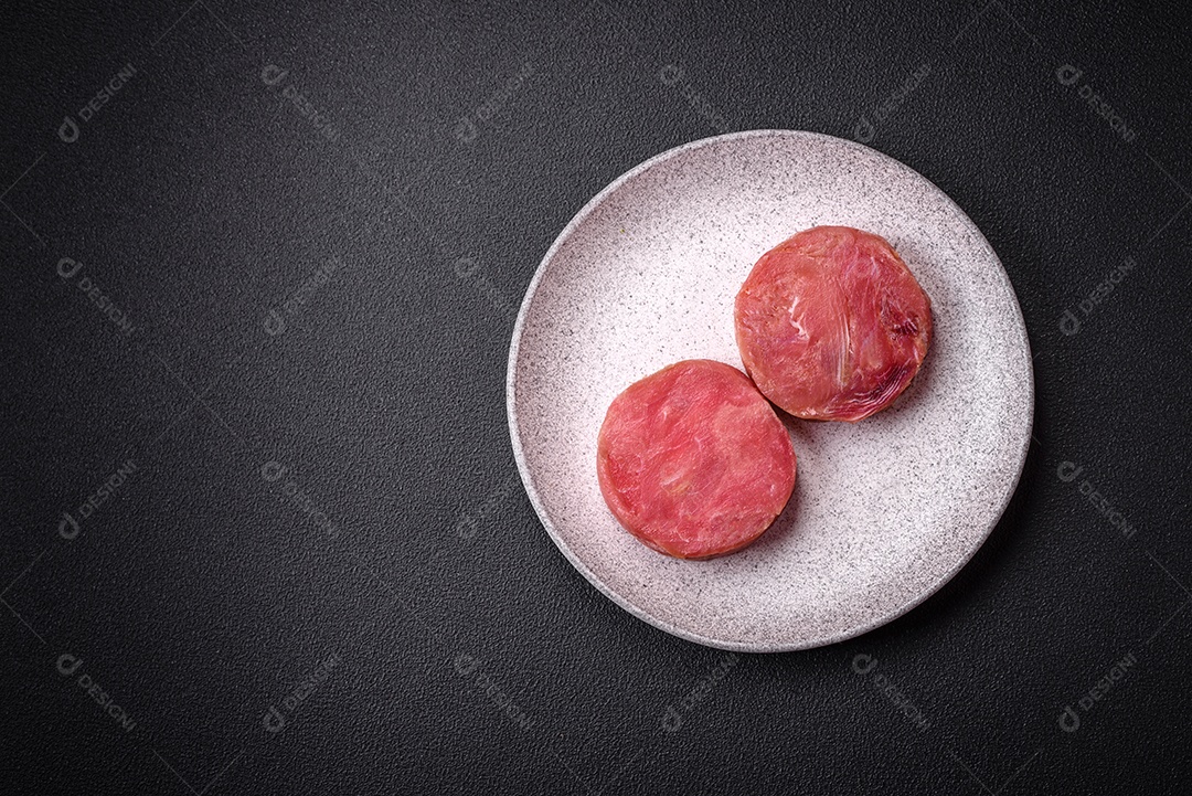 Bifes redondos de atum suculento cru com sal e especiarias sobre um fundo escuro de concreto