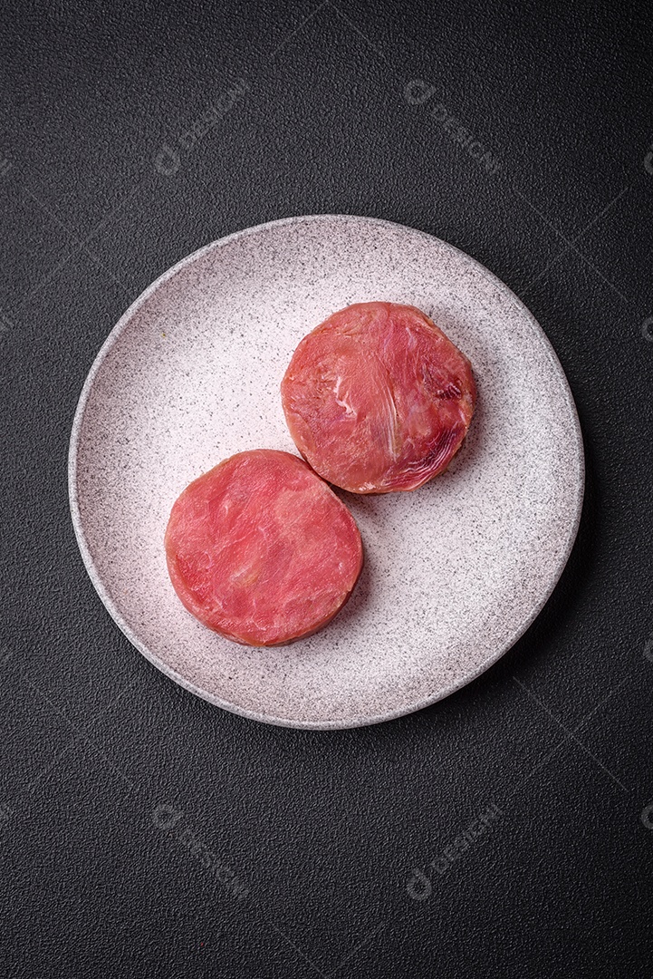 Bifes redondos de atum suculento cru com sal e especiarias sobre um fundo escuro de concreto