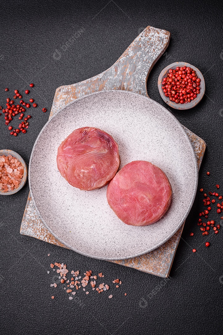 Bifes redondos de atum suculento cru com sal e especiarias sobre um fundo escuro de concreto