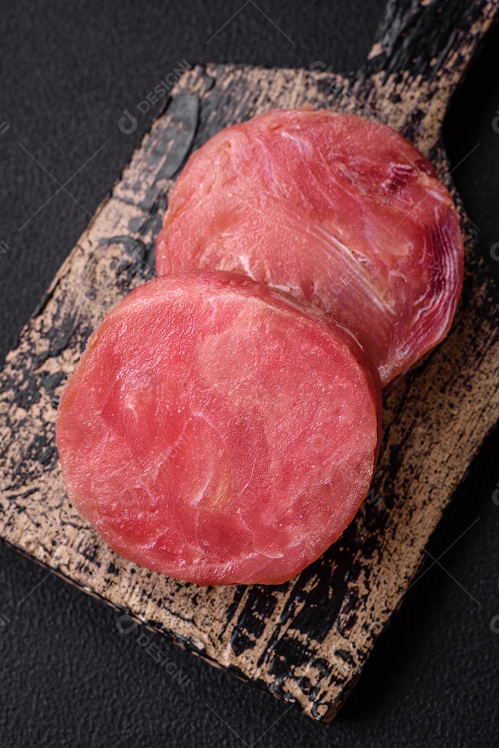 Bifes redondos de atum suculento cru com sal e especiarias sobre um fundo escuro de concreto