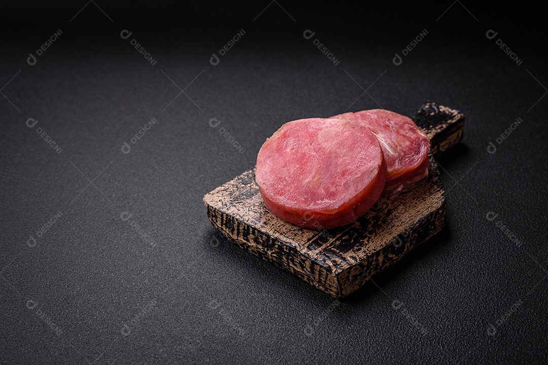 Bifes redondos de atum suculento cru com sal e especiarias sobre um fundo escuro de concreto