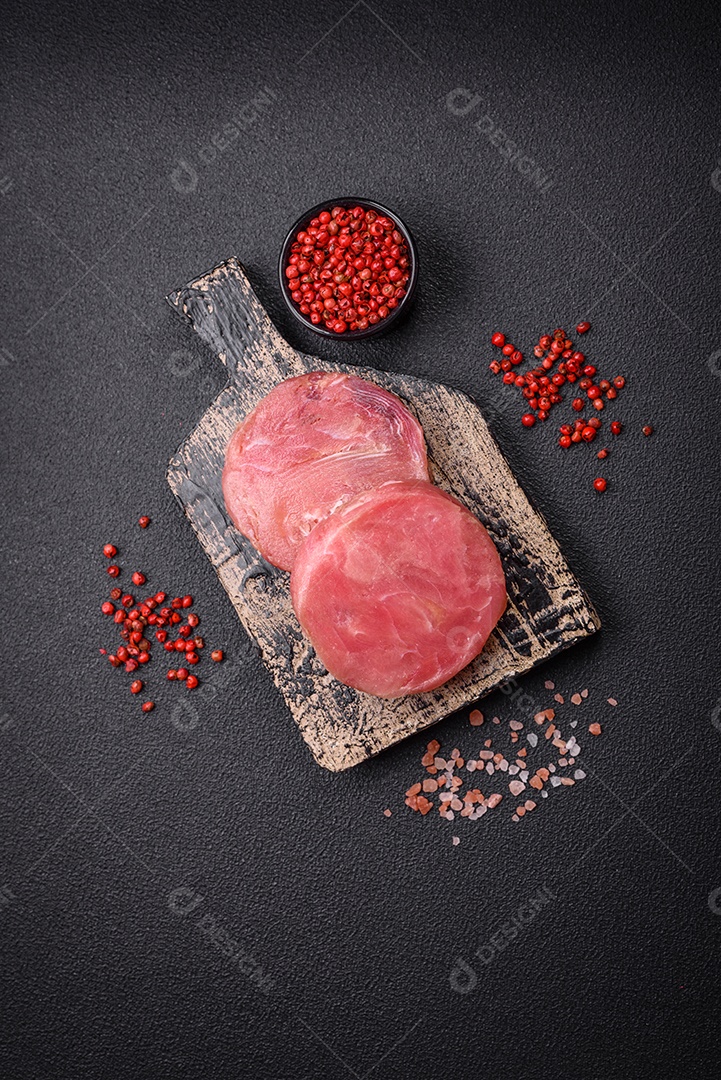 Bifes redondos de atum suculento cru com sal e especiarias sobre um fundo escuro de concreto