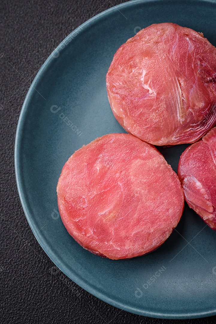 Bifes redondos de atum suculento cru com sal e especiarias sobre um fundo escuro de concreto