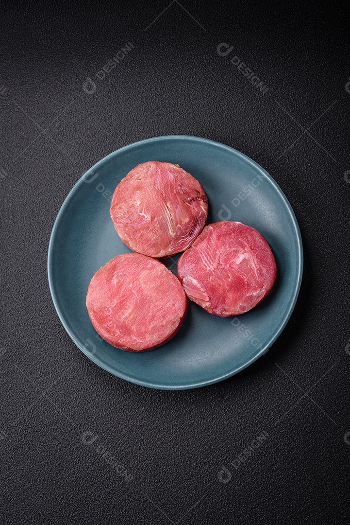 Bifes redondos de atum suculento cru com sal e especiarias sobre um fundo escuro de concreto