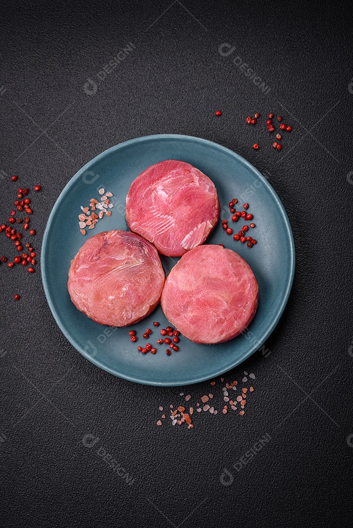 Bifes redondos de atum suculento cru com sal e especiarias sobre um fundo escuro de concreto