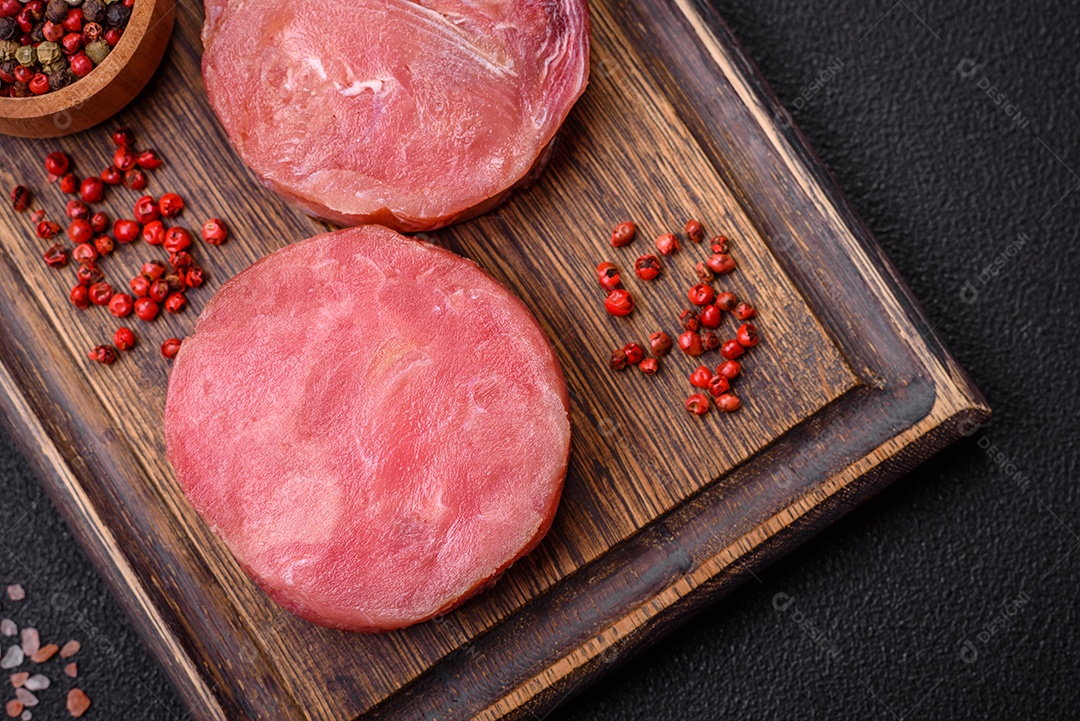 Bifes redondos de atum suculento cru com sal e especiarias sobre um fundo escuro de concreto